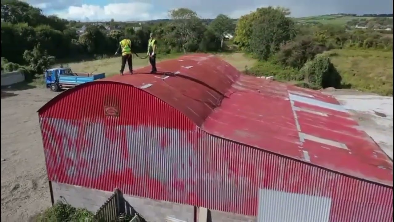 Professional worker using airless spray painting equipment on a farm building