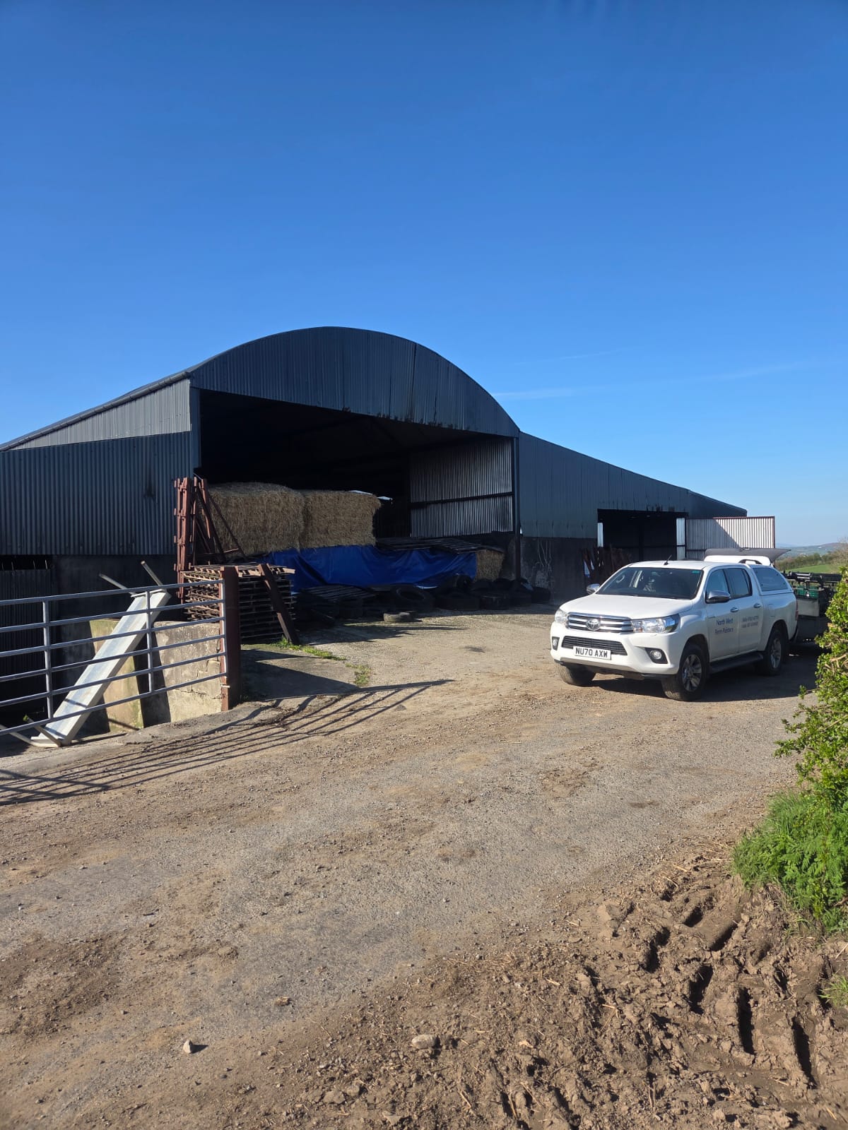 Northwest Farm Sprayers Hilux at a farm with large barn and hay bales