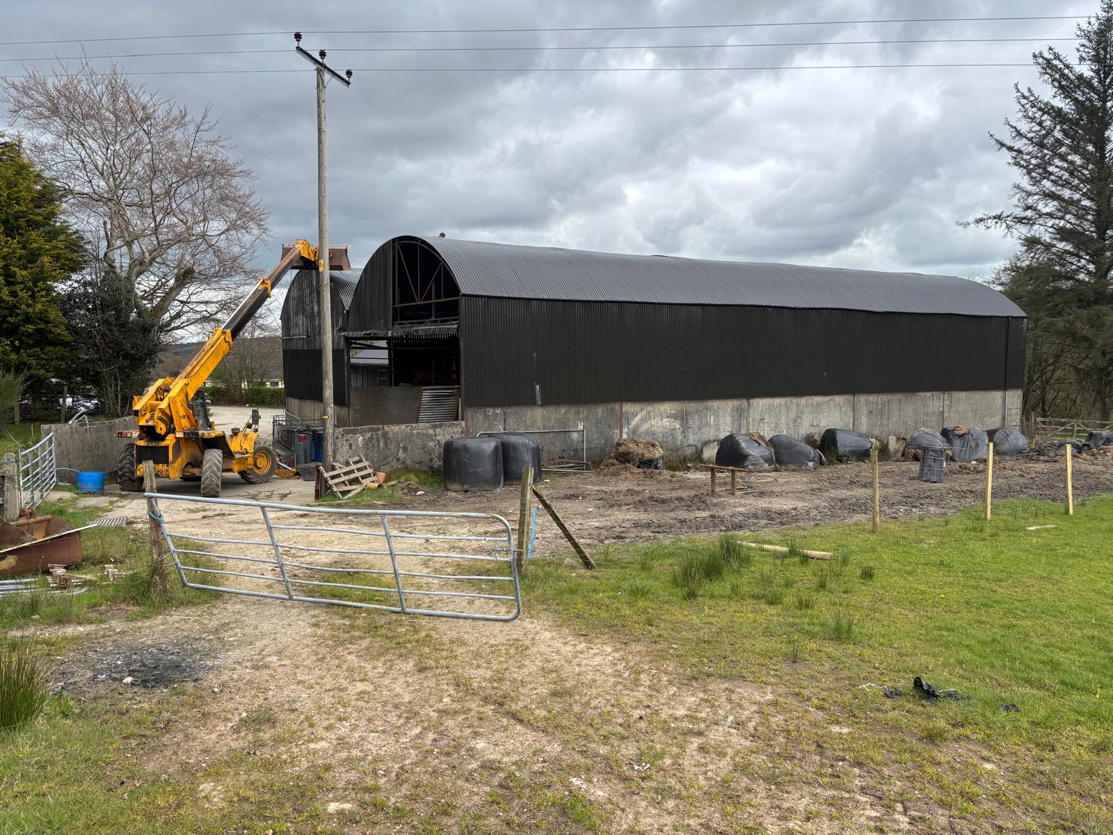 Large freshly painted dark barn with JCB and green fields