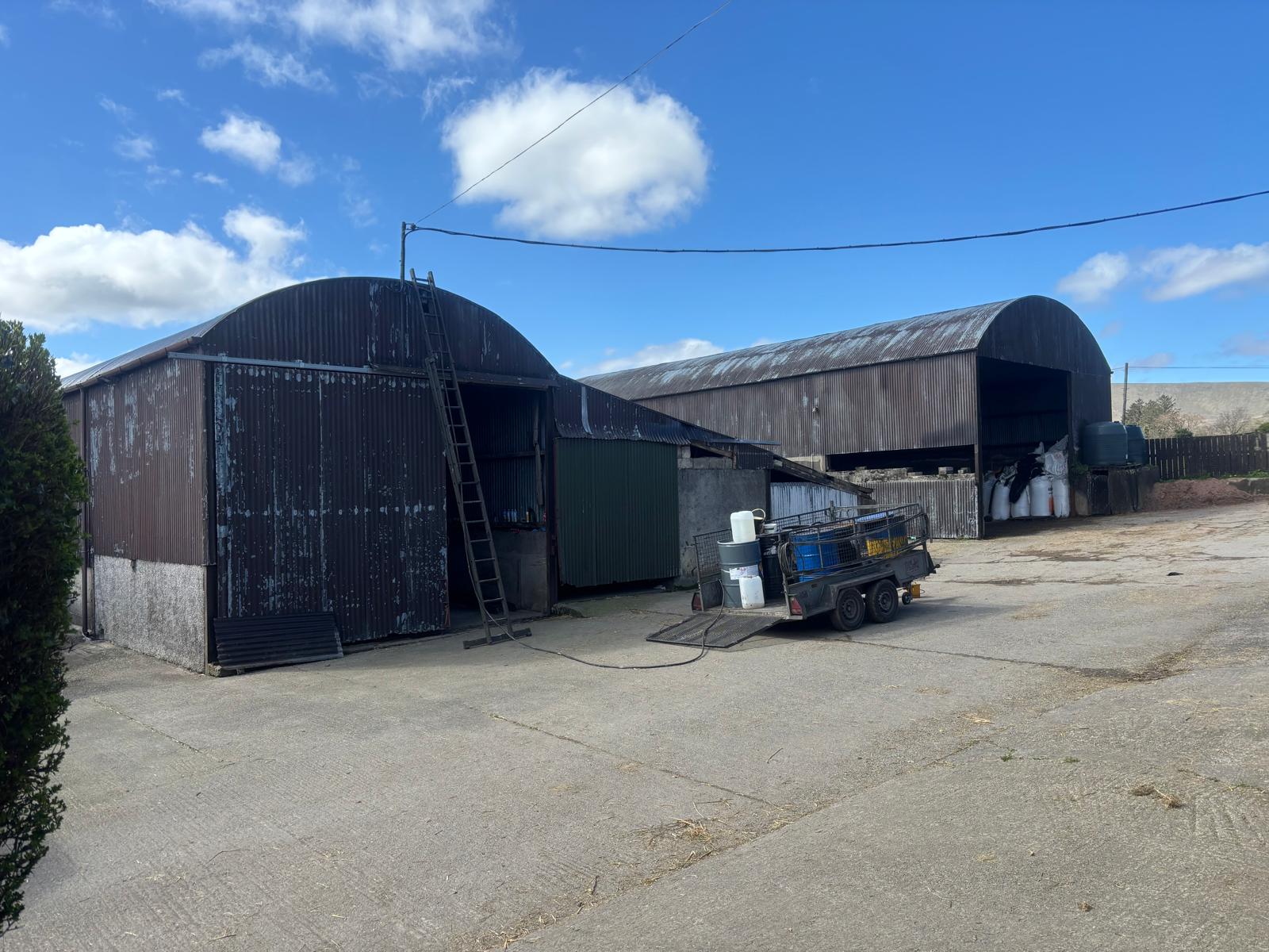 Two round-roof farm sheds with ladder and painting supplies ready